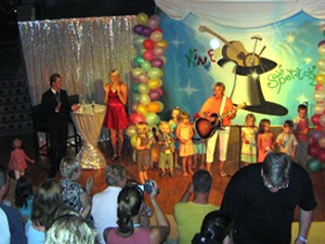 Karin Meier spielt Gitarre,
rechts und links von ihr Kinder auf der Bühne. Die Eltern klatschen und
filmen im Publikum.
