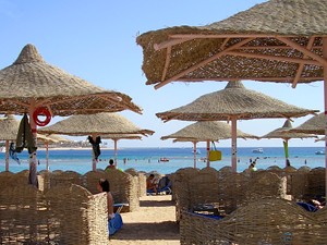 Das Meer und der Strand mit
großen geflochtenen Sonnenschirmen und geflochtenen Stellwänden.