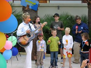 Karin spielt Gitarre. Die Kinder auf der Bühne begleiten sie mit kleinen Instrumenten.