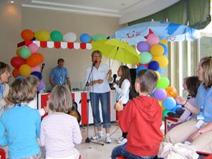 Karin mit Regenschirm und Kind singend bei einem Auftritt vor Kindern.