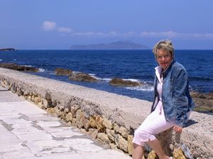 Karin Meier sitzt auf einer Mauer vor dem weitem, blauen Meer.